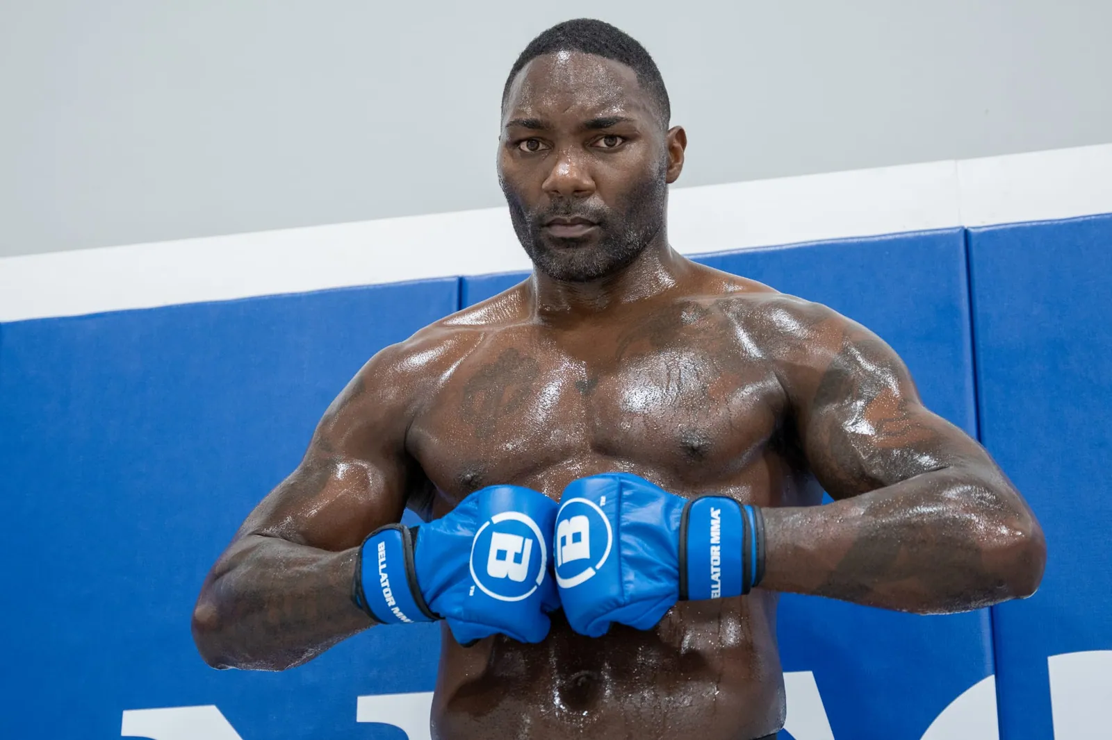 Anthony Johnson in a guarded stance wearing blue Bellator MMA gloves.