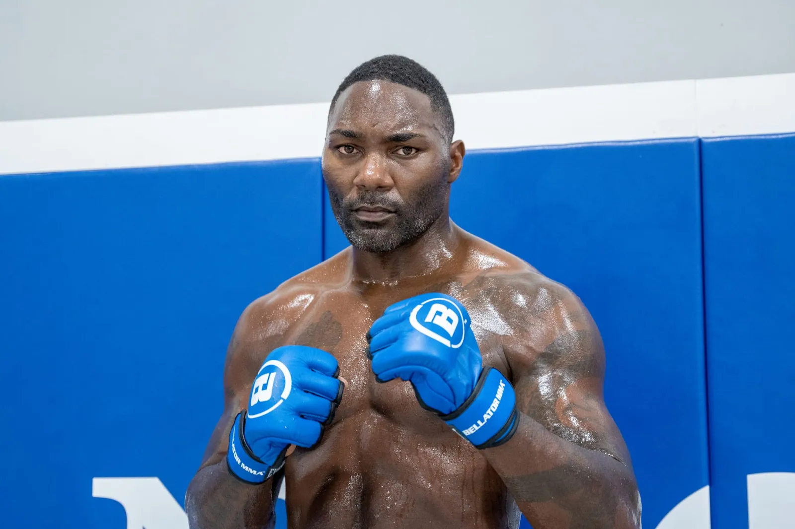 Anthony Johnson mid-session in blue Bellator MMA gloves, shoulders squared to camera.